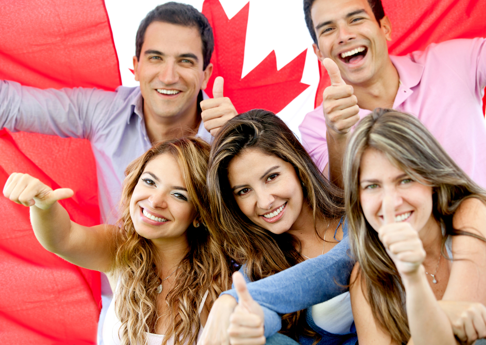 Group of young people with Canada flag in background.