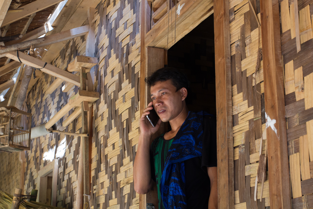 Baduy man speaking on the  phone at his house