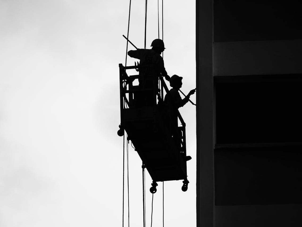 Black and White Photo of Men Working on a Hanging Platform