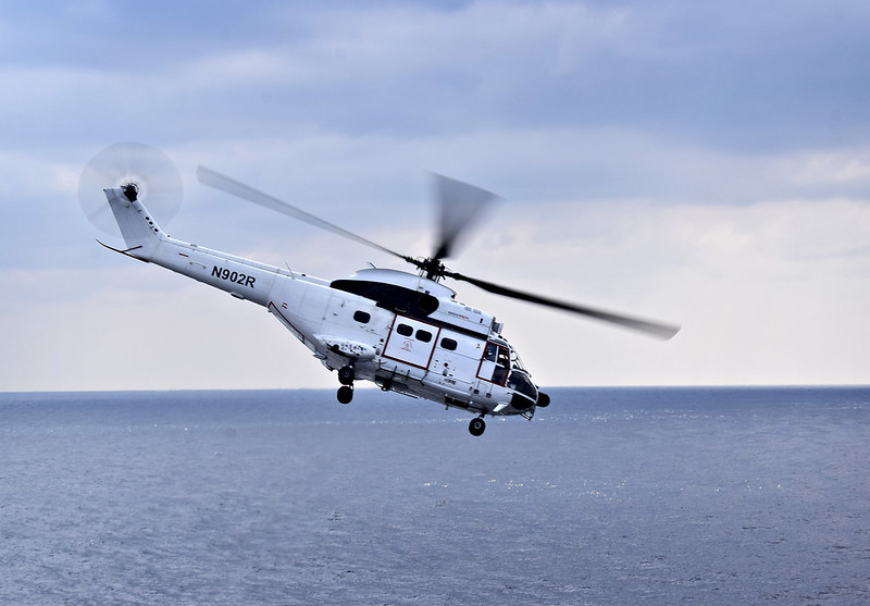 Close Up Photo of a white helicopter flying over the sea.