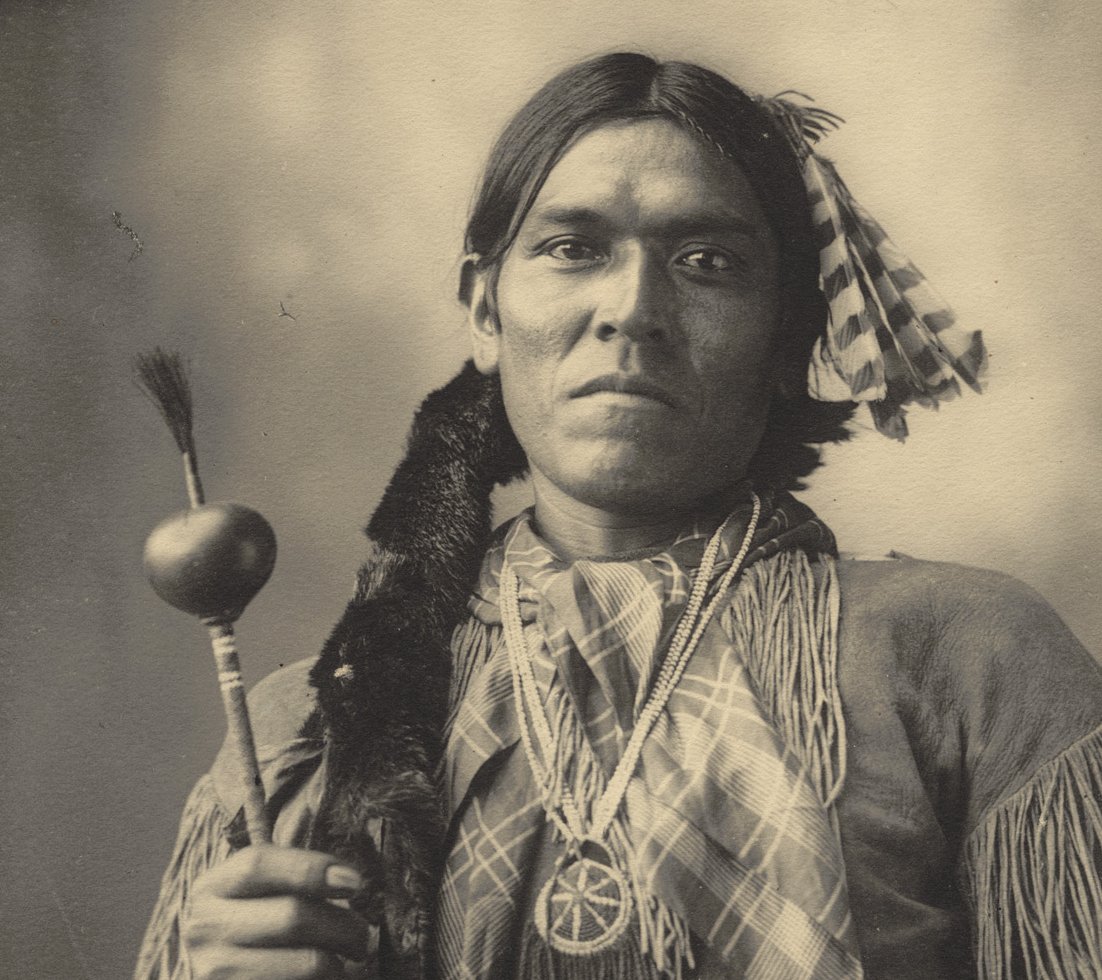 Grayscale Portrait Photo of Native American man in traditional clothing.