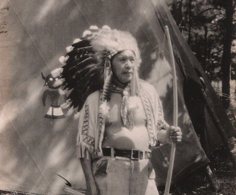 Grayscale Portrait Photo of Native American with bow in traditional clothing