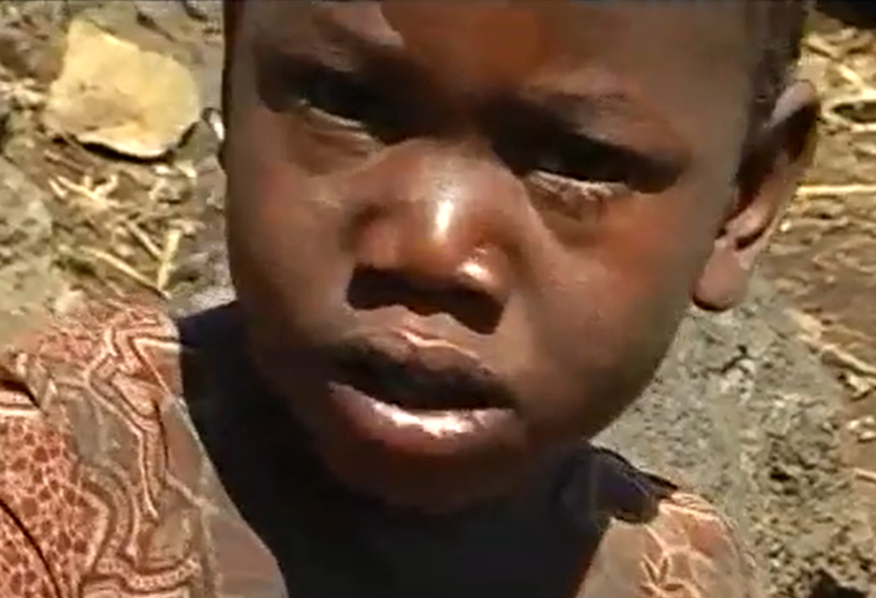 Screenshot of Batwa tribe kid outside - from The Batwa Legacy (2011)