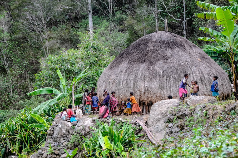 children and women gather in a common hut