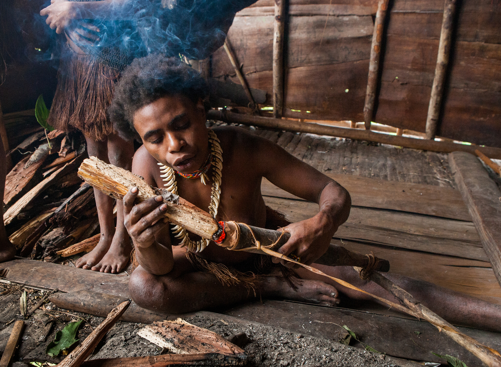 Korowai tribe woman smokes a traditional pipe