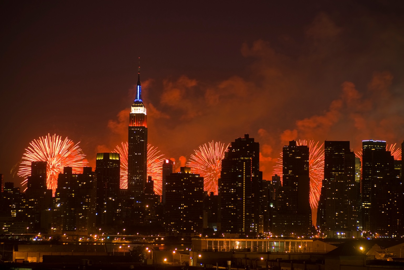 The Manhattan skyline and the Macy's Fourth of July fireworks display in the Hudson River behind it.