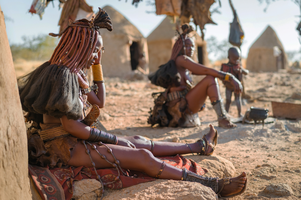 Himba women sitting outside their huts in a traditional Himba village