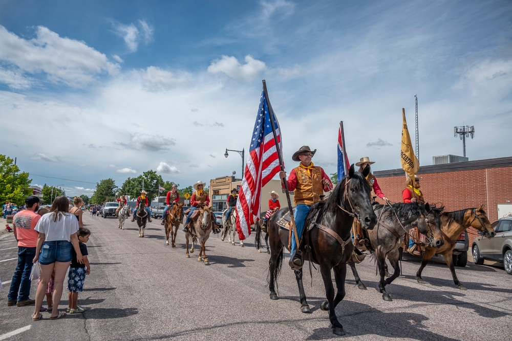 Cowboy riding a horse in the Fourth of July parade carrying an American flag