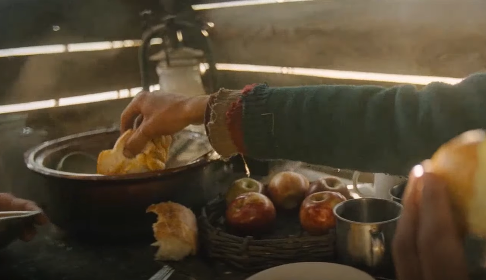 Screenshot of man eating bread and fruit - from Society of the Snow (2023)