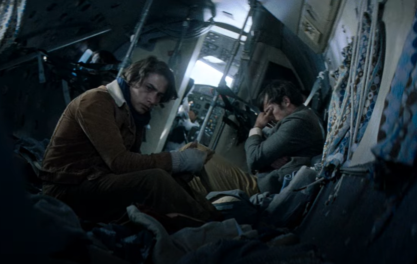 Screenshot of injured people looking scared in the plane body - from Society of the Snow (2023)