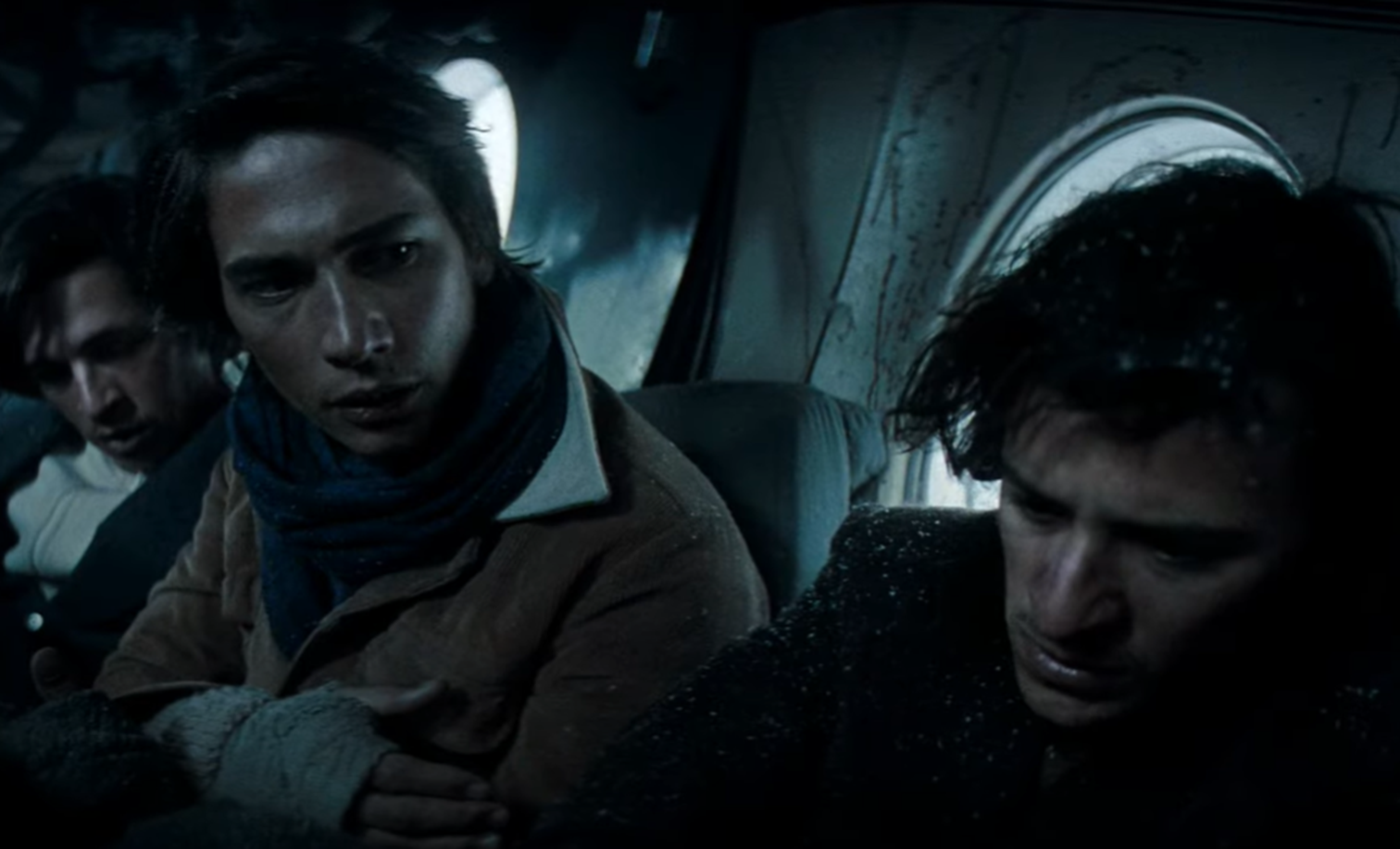 Screenshot of injured people looking scared in the plane body - from Society of the Snow (2023)