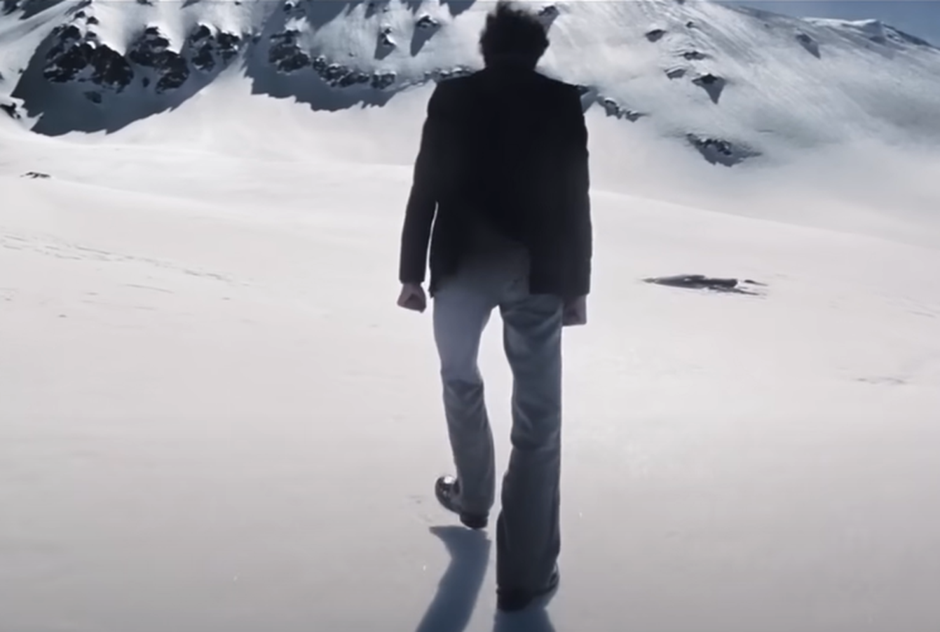 Screenshot of man walking on the snow - from Society of the Snow (2023)