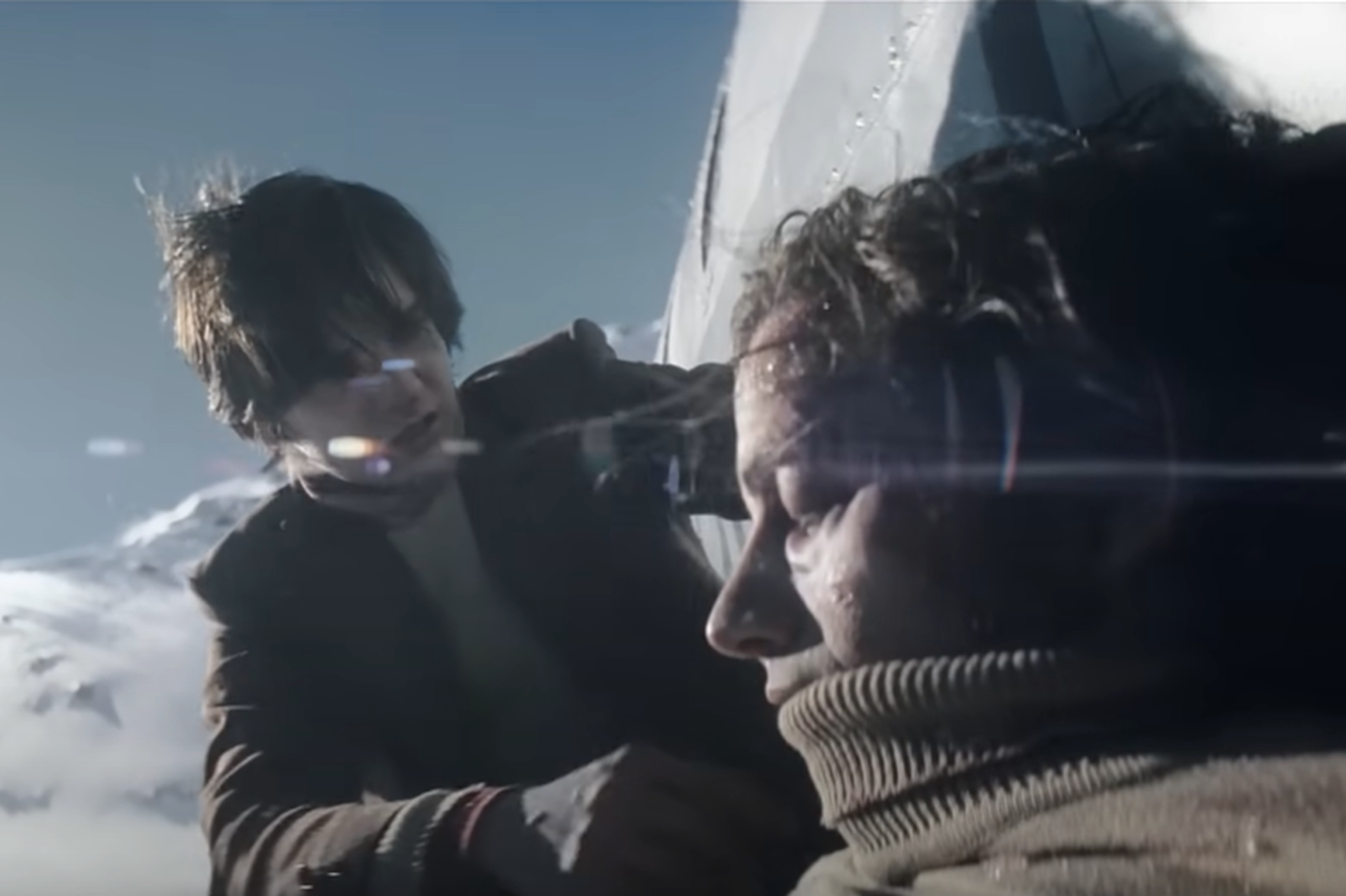 Screenshot of man helping injured people in the snow - from Society of the Snow (2023)