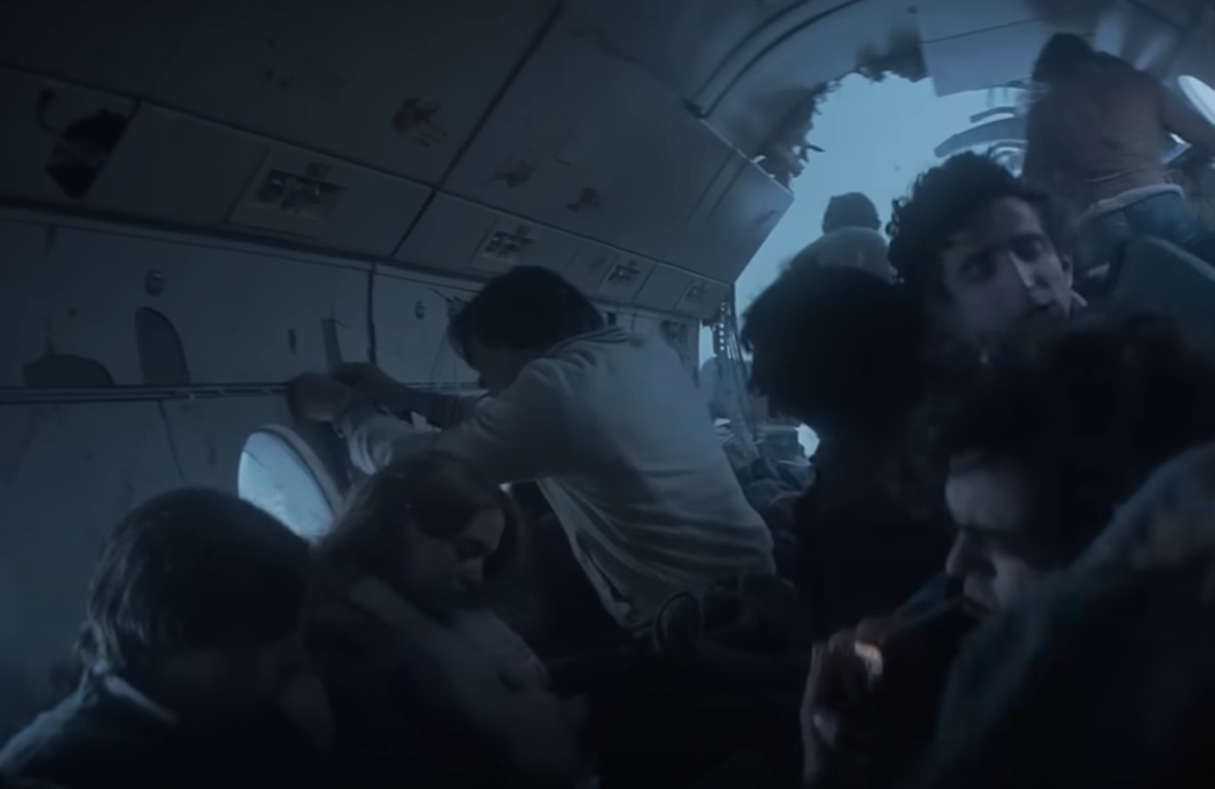 Screenshot of destroyed plane body in the snow with people in side - from Society of the Snow (2023)