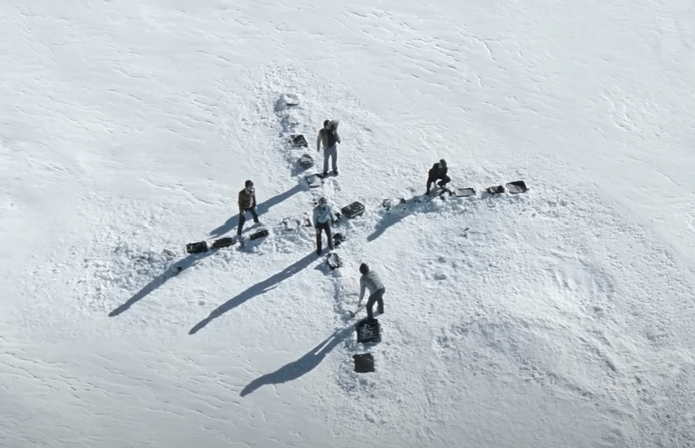 Screenshot of people making X sign in the snow - from Society of the Snow (2023)