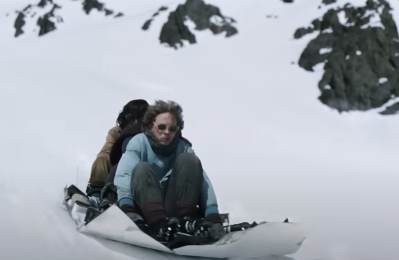 Screenshot of people seating on the metal plate outside - from Society of the Snow (2023)