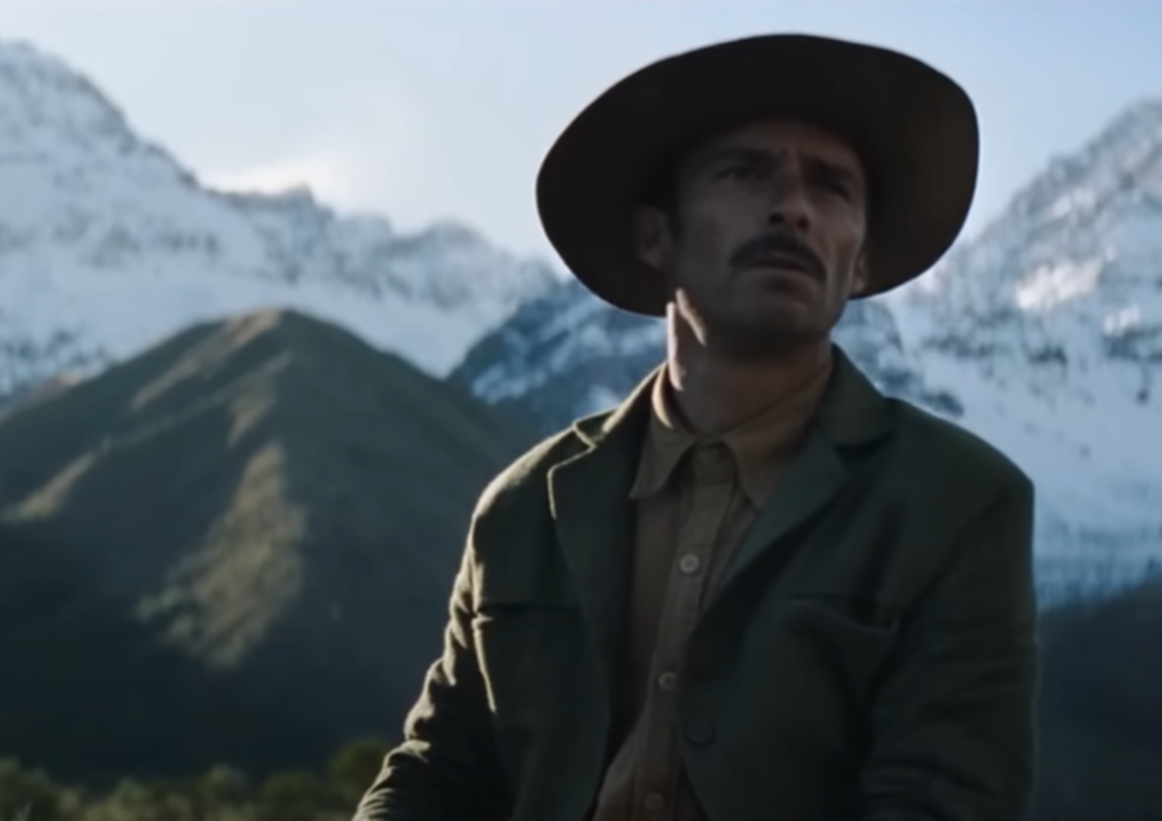 Screenshot of man with a hat looking at side - from Society of the Snow (2023)