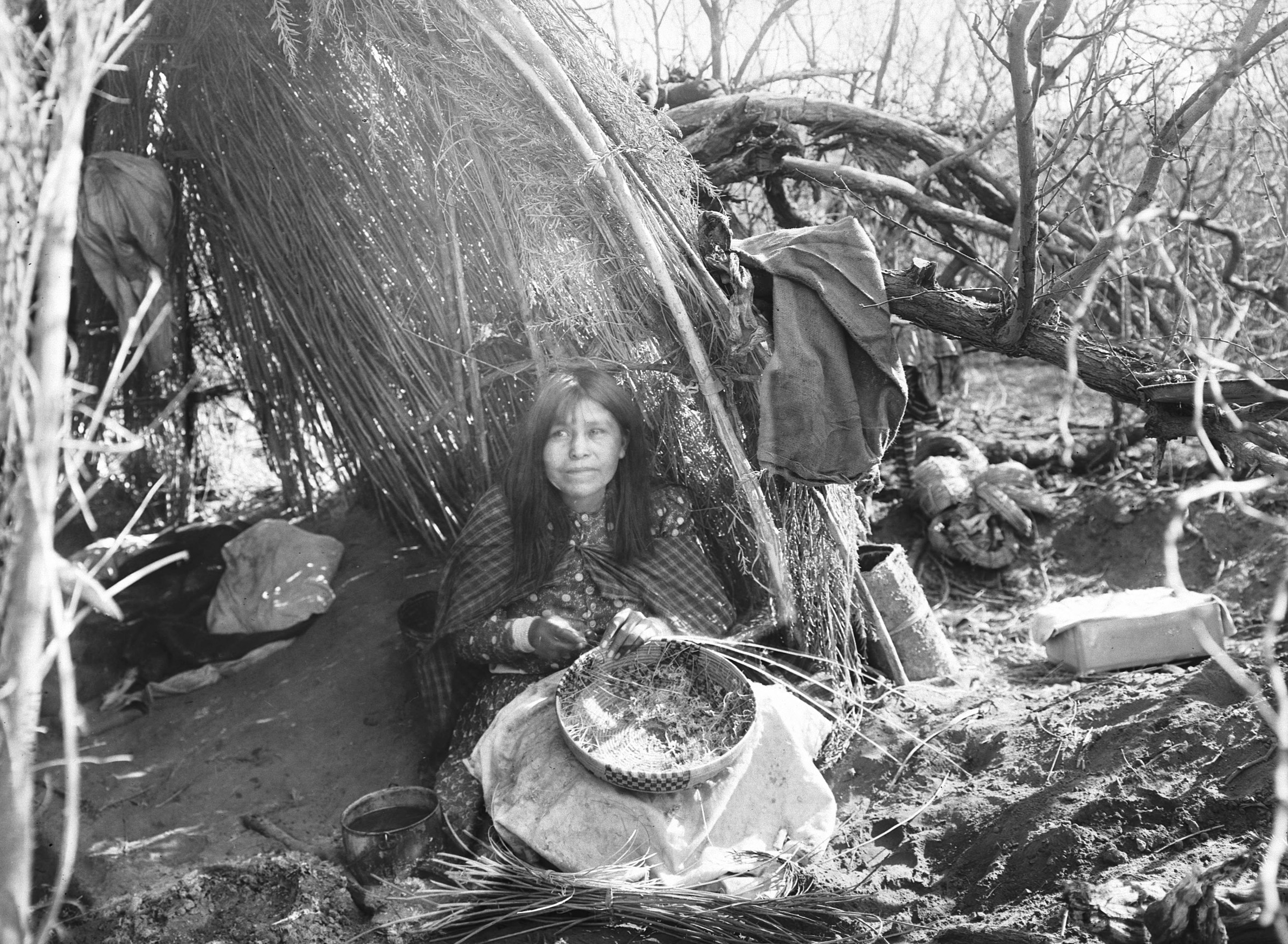 Portrait Of An Apache Indian Woman next to a house
