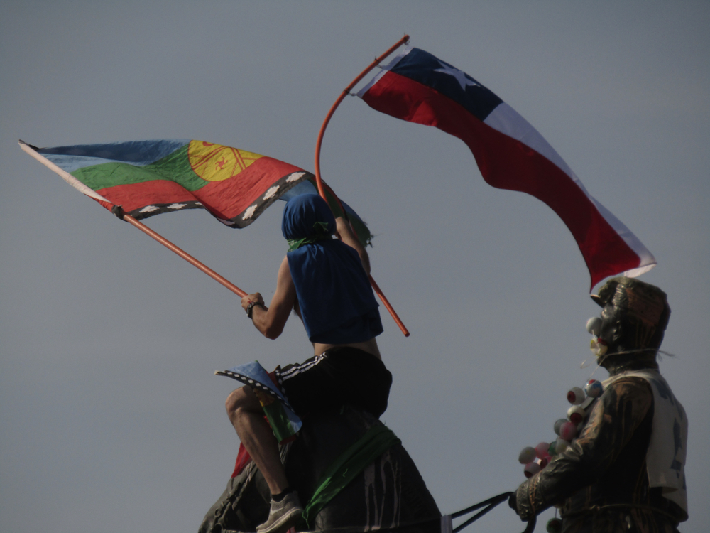 A young protester waves a Chilean flag and a Mapuche flag