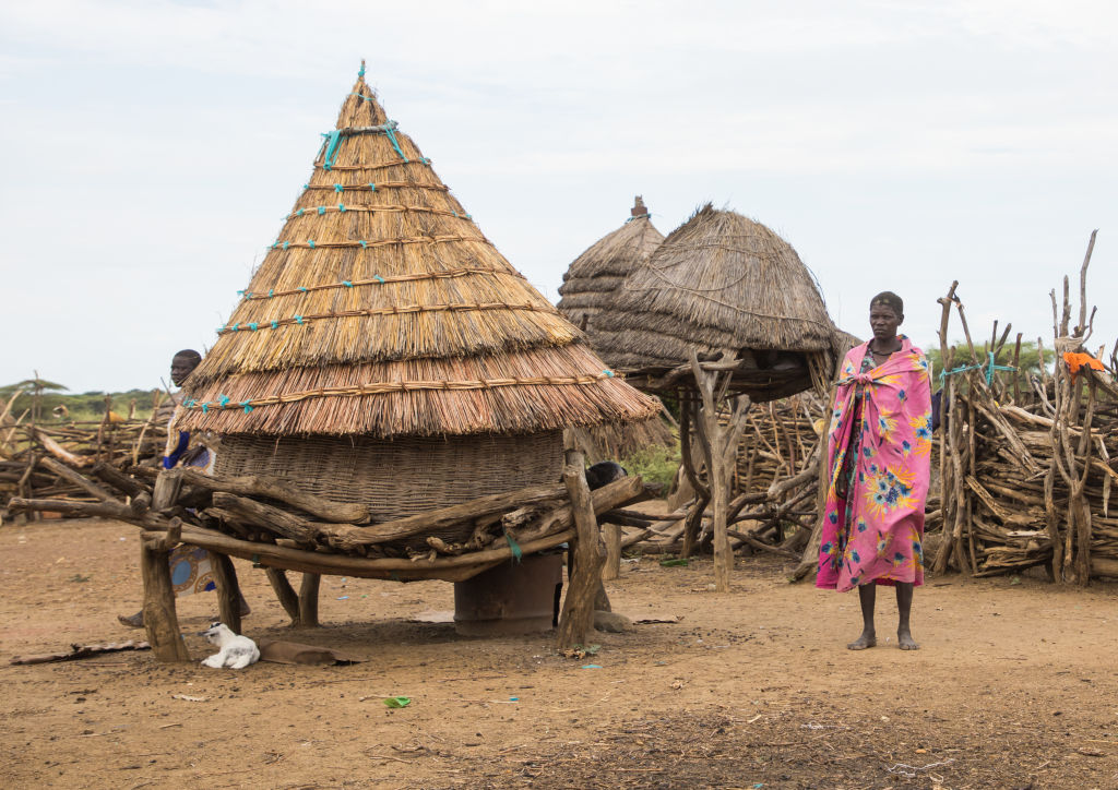 Toposa tribe woman standing near a hut