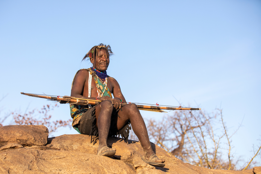 Hadzabe man resting with his bow and arrow on his lap - 2019