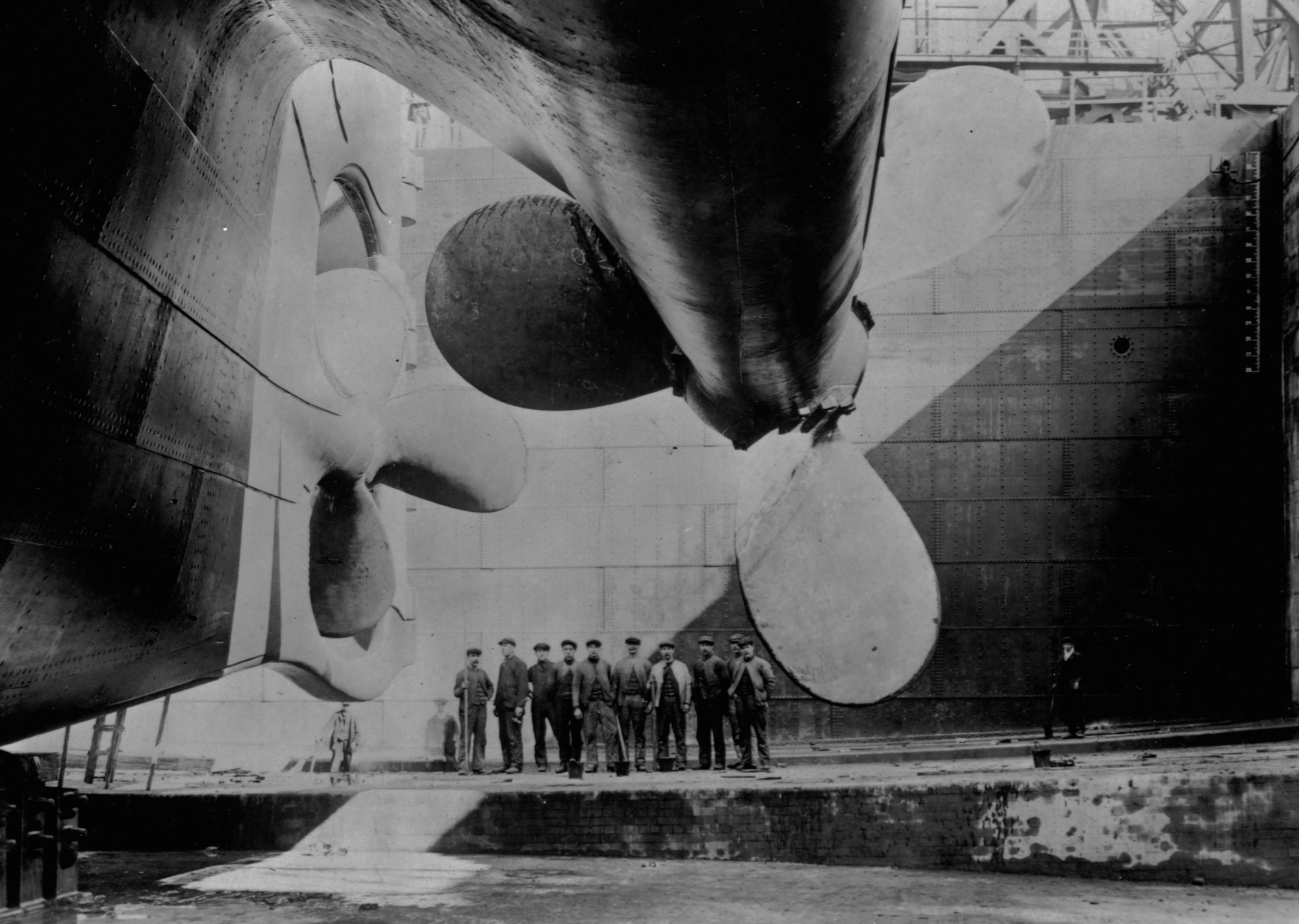 Workers pose near the port and centre propellers of the ocean liner, RMS Olympic