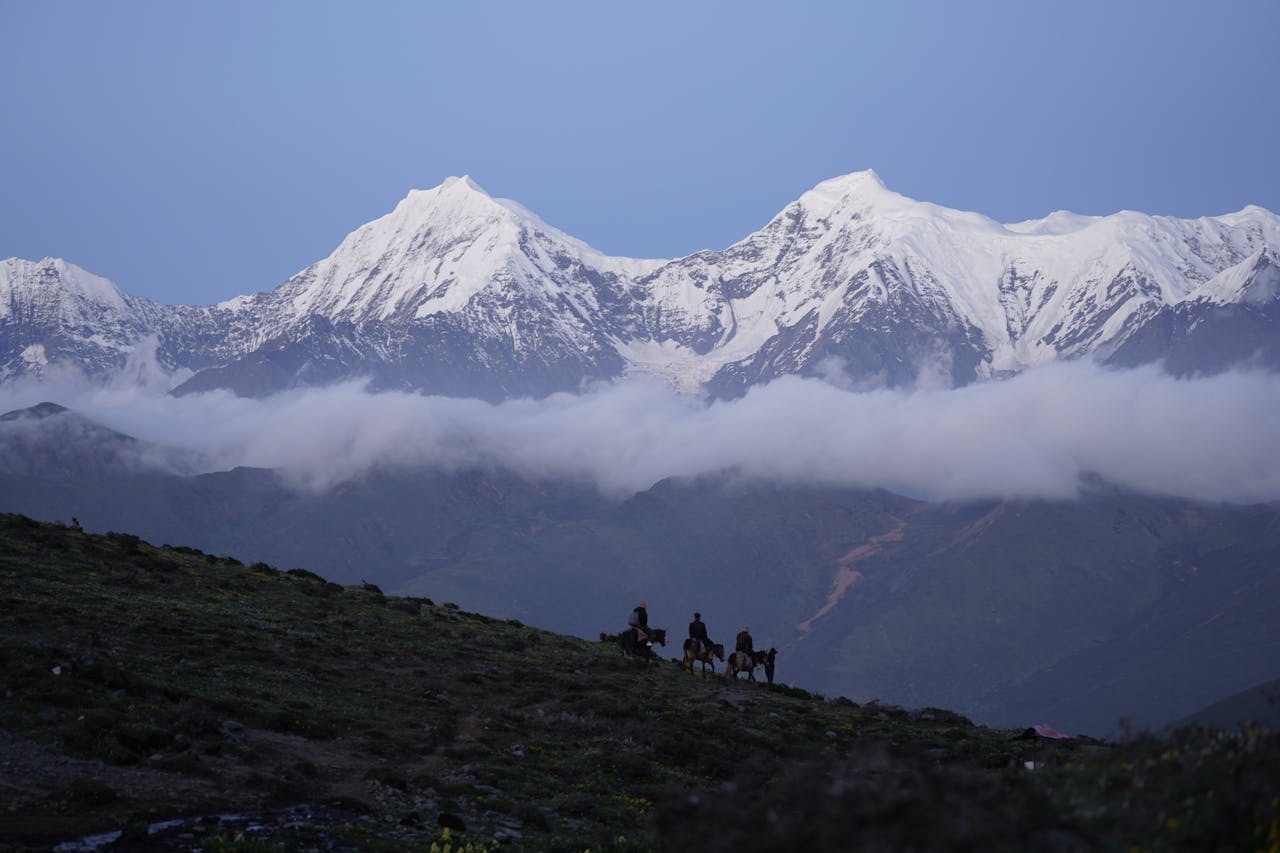 People Horseback Riding on Mountain Slope