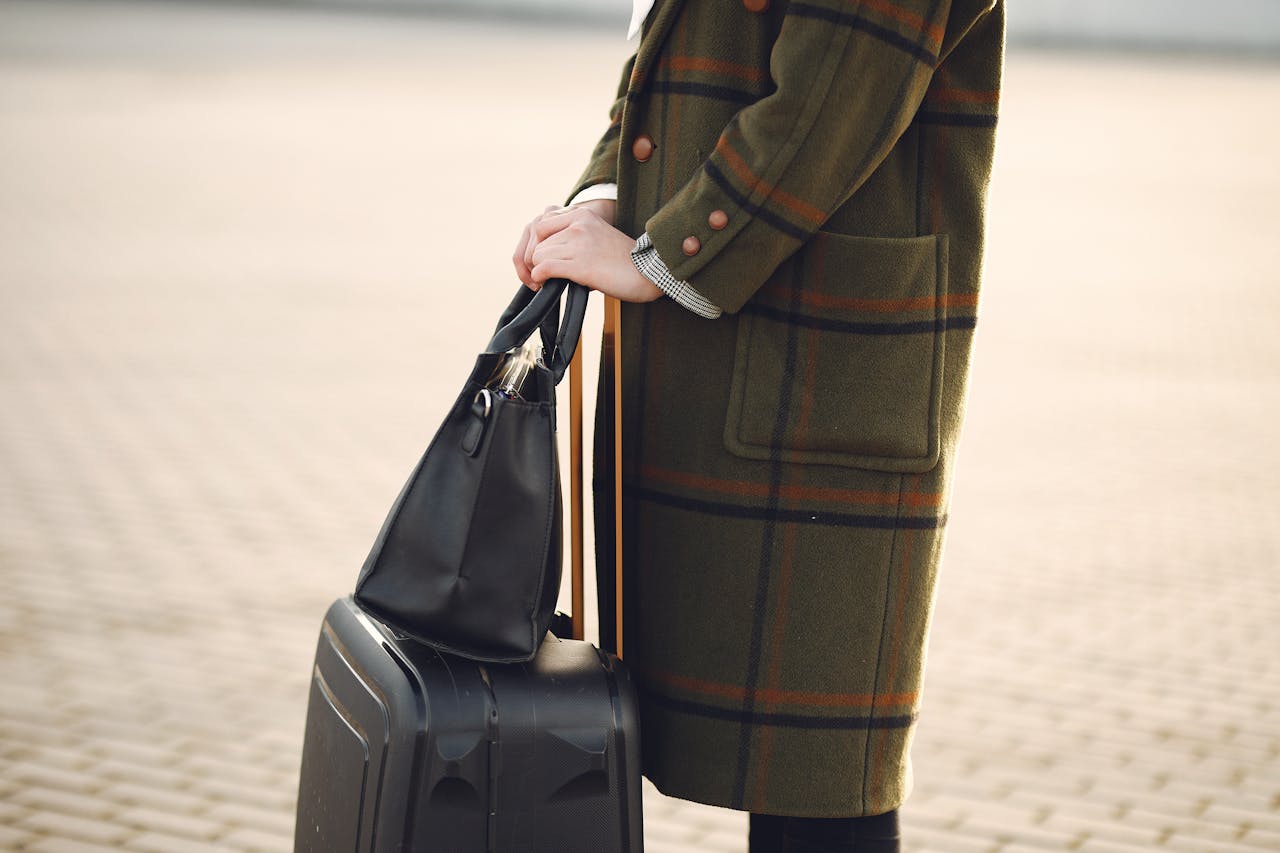 Crop stylish woman with baggage standing on street