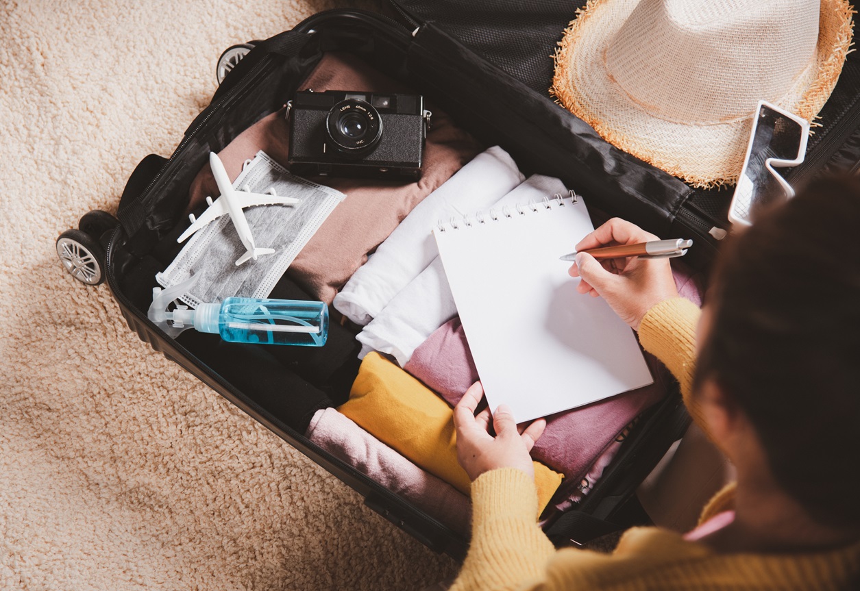 Woman writing paper take note and packing suitcase to vacation