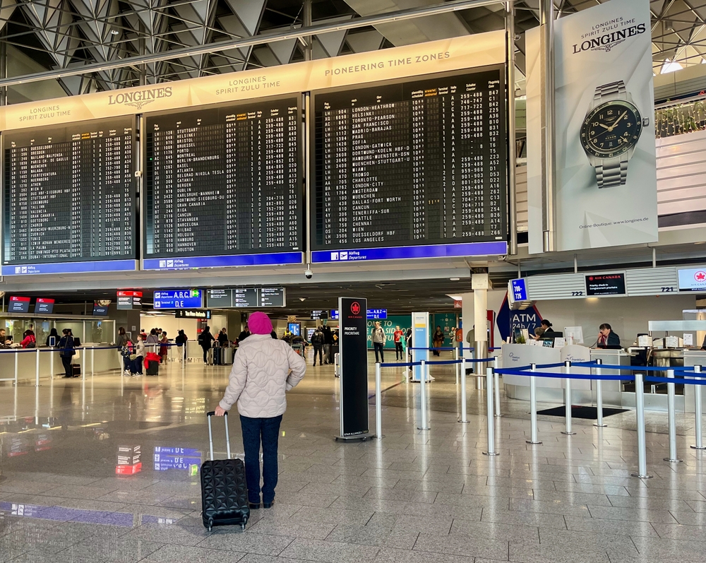 Senior woman standing in airport area looking at timetable - 2023