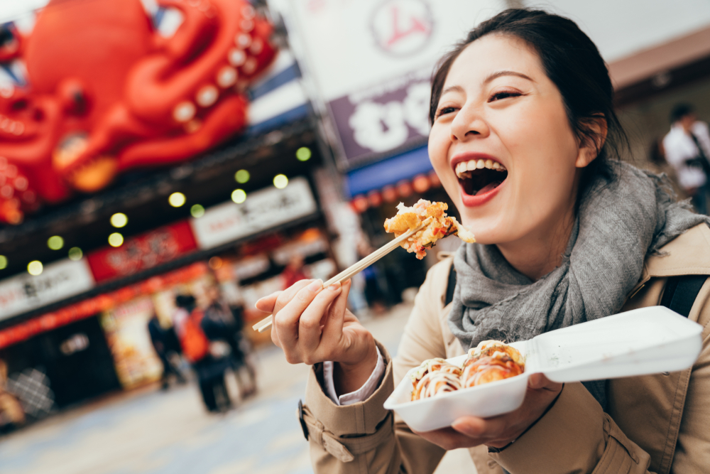 Young woman holding box of Japanese local street food.