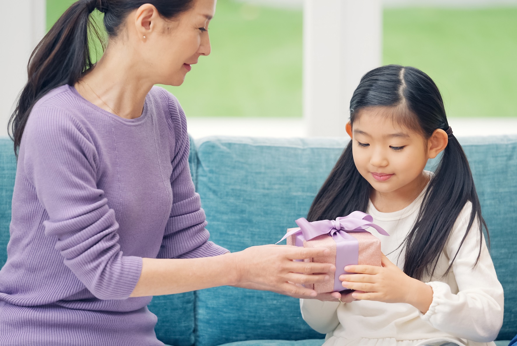 Asian woman giving present to a girl.