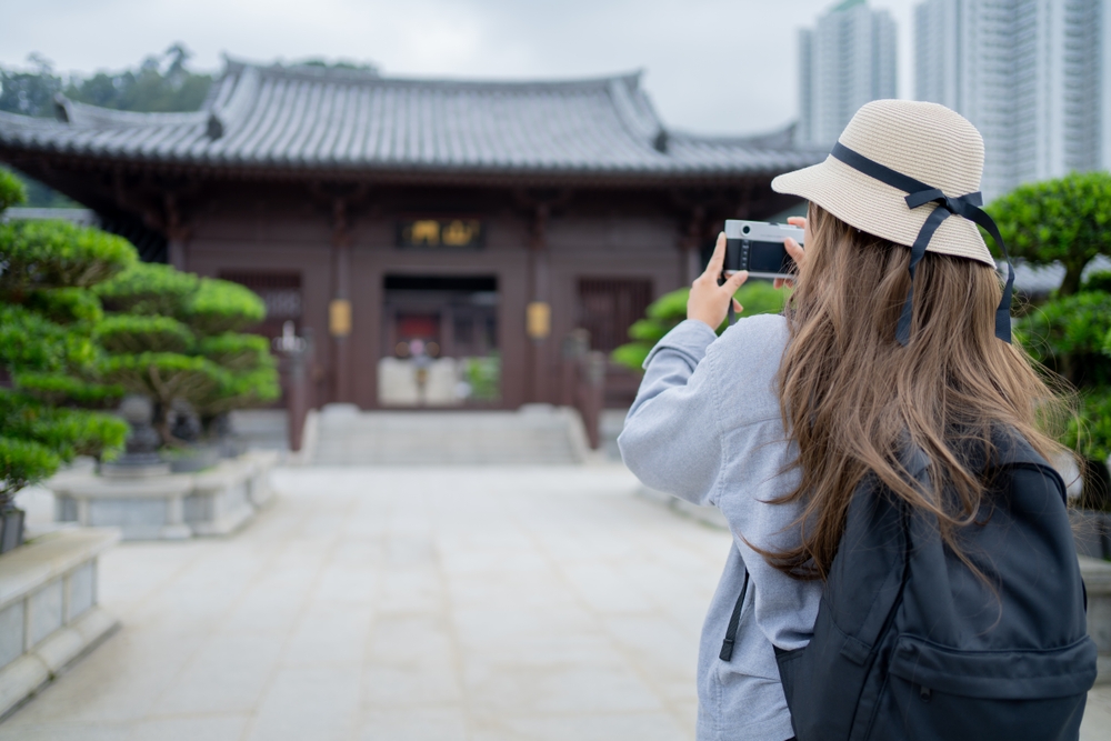 Asian tourist is taking pictures with her camera.