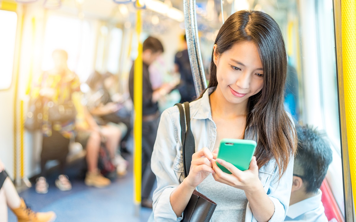 Woman holding mobile phone inside train.