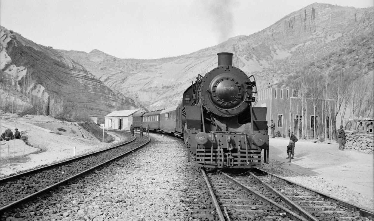 Somewhere in Iran. An American engine transporting allied aid for Russia, stopping at a station rimmed by mountains.jpeg