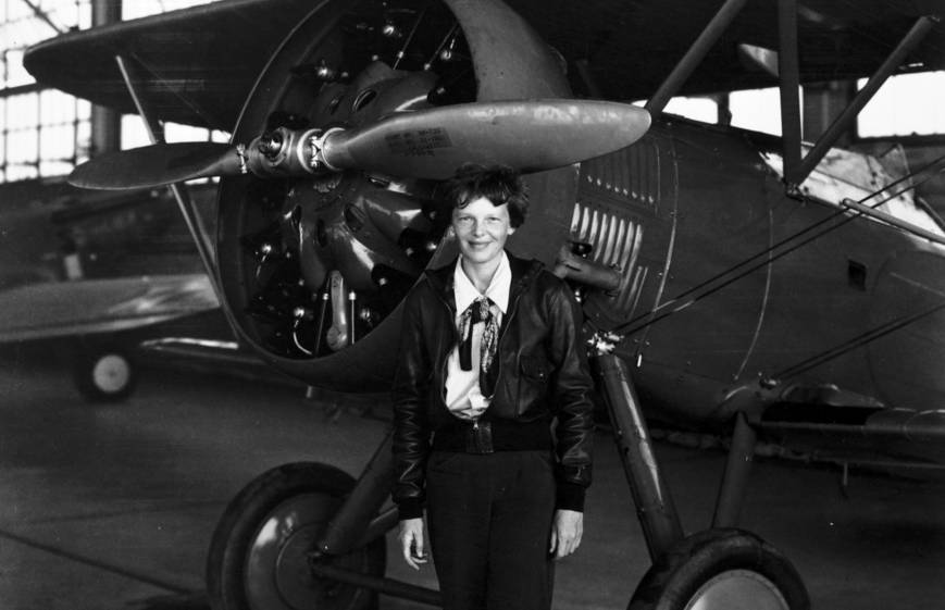 Amelia Earhart posing in front of an aircraft