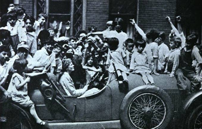 A photo of Amelia Earhart in her car with children around