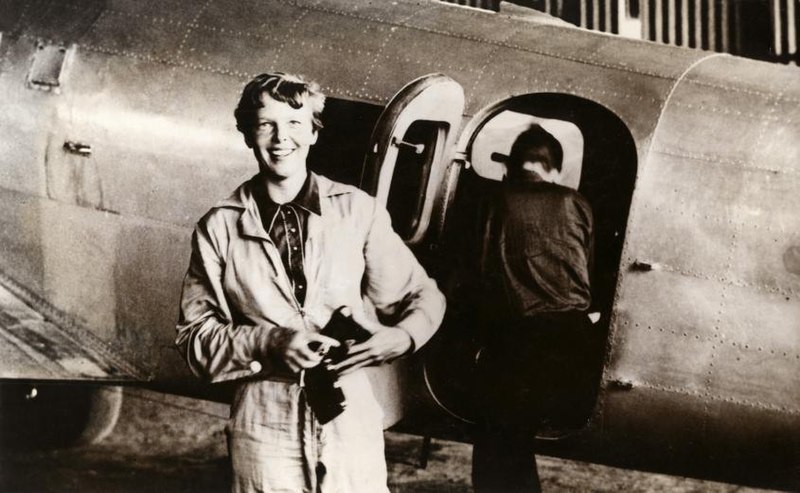 Amelia Earhart standing by a plane with Fred Noonan