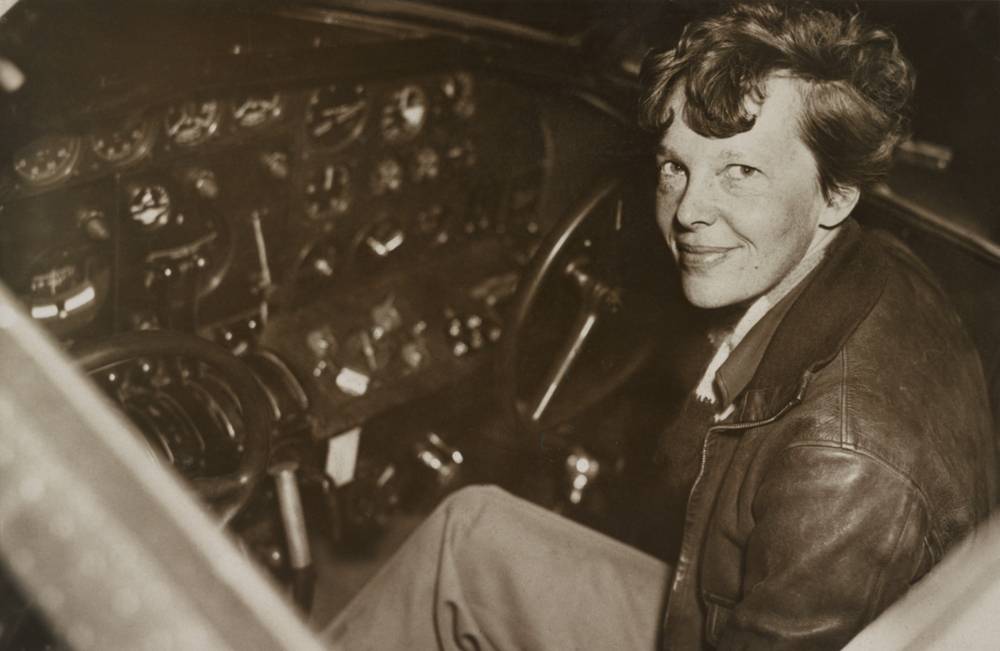 Amelia Earhart sitting in the cockpit of her plane