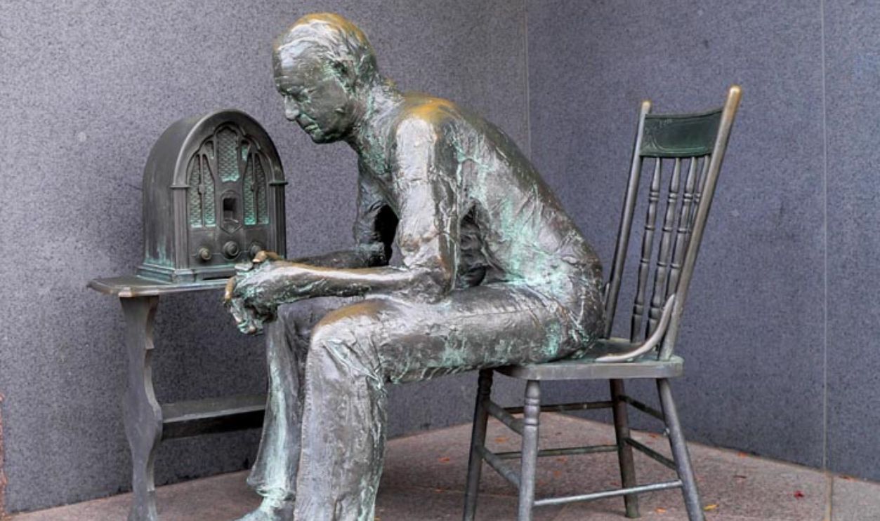 Bronze sculpture of a man listening to the 1930s valve radio.
