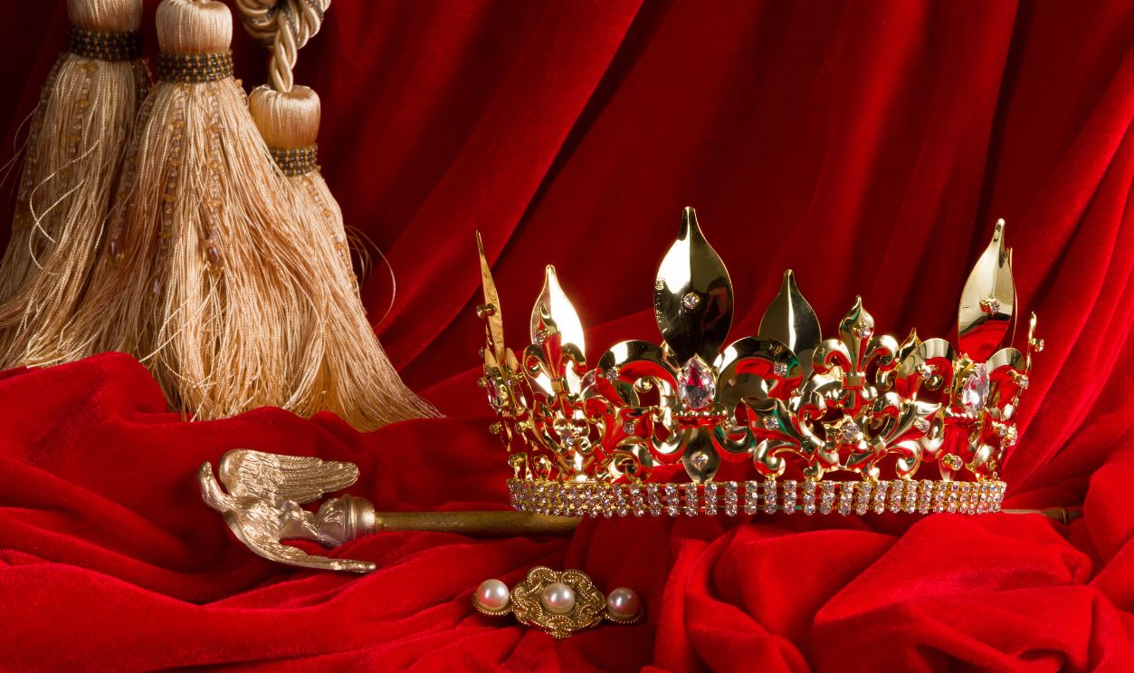 Golden king's crown and scepter on red velvet