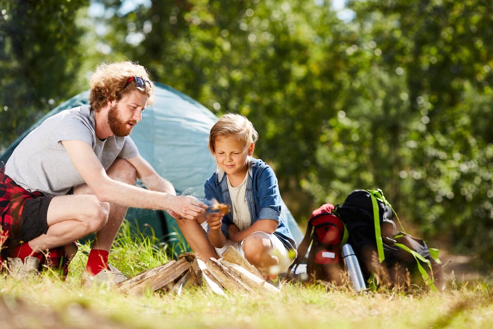 Man showing his son how to make campfire