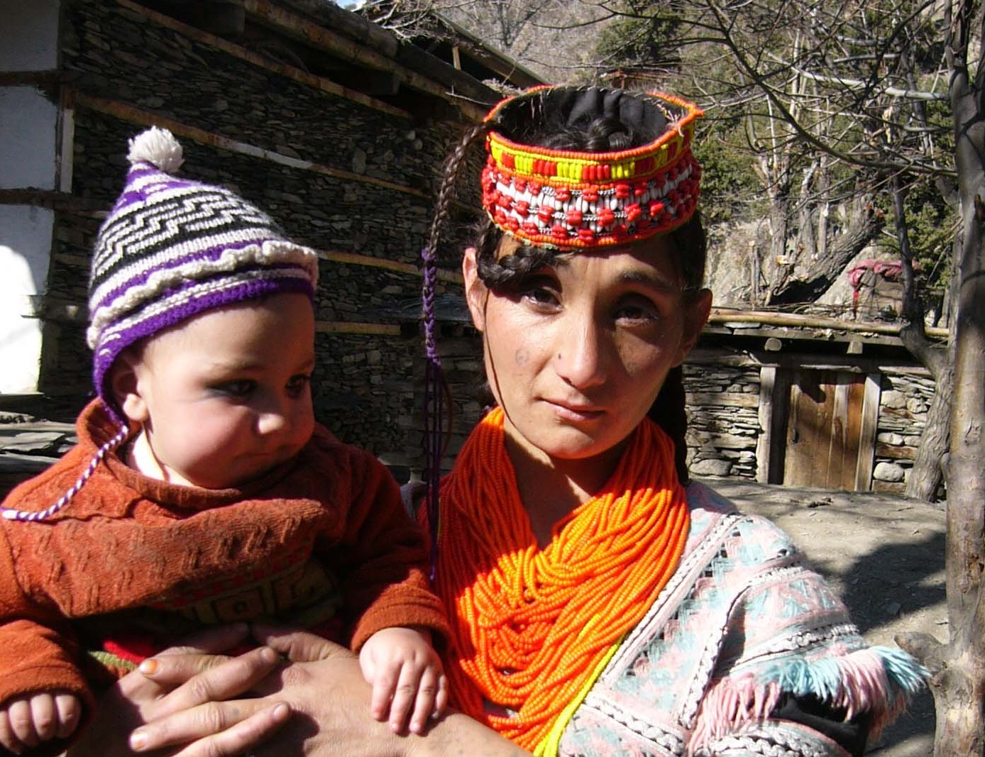 Kalash woman holding a baby outside.