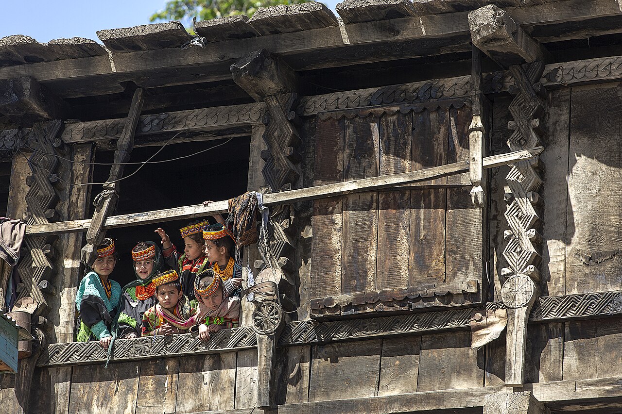 Kalash Girls Looking From The Window Of Traditional Wood Home With Beautiful Carvings