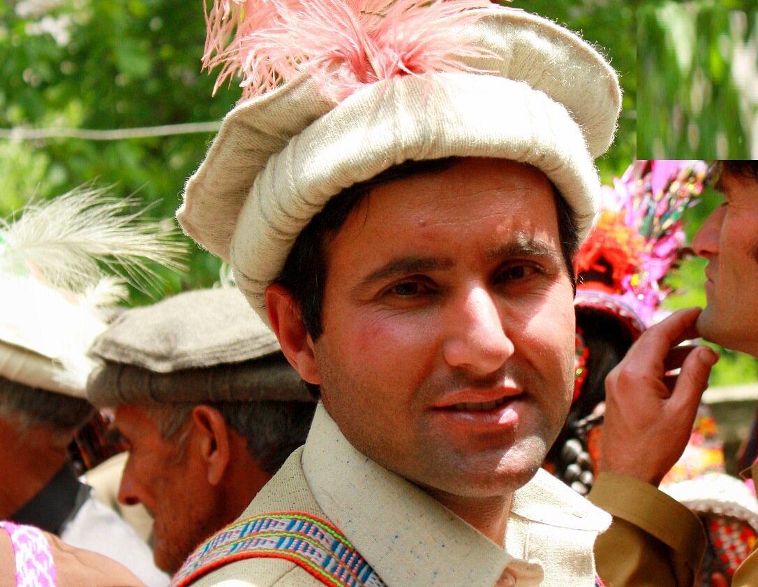 Kalash man sporting a long pink plume in his Chitral topi