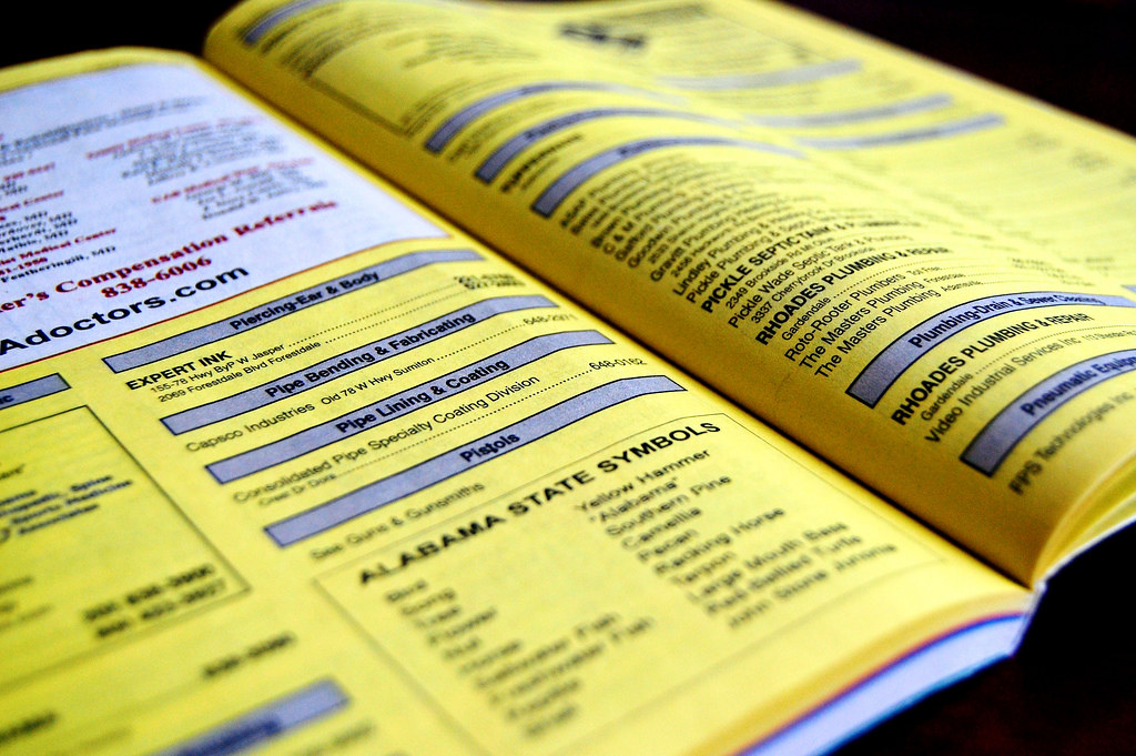 A close-up image of an open yellow-paged phonebook