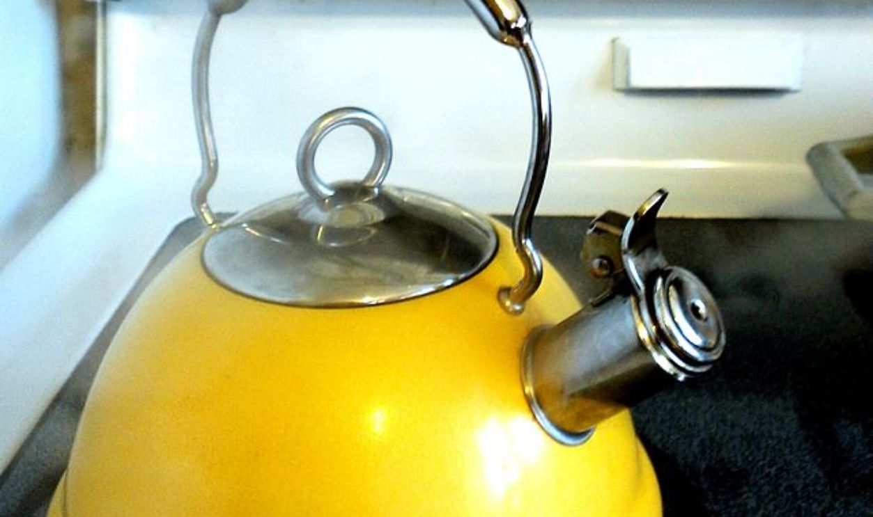 Yellow kettle with boiling water on stovetop