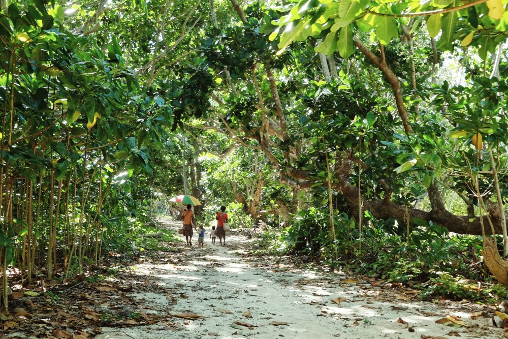 Photo of Women walking home with kids on the sea shore path