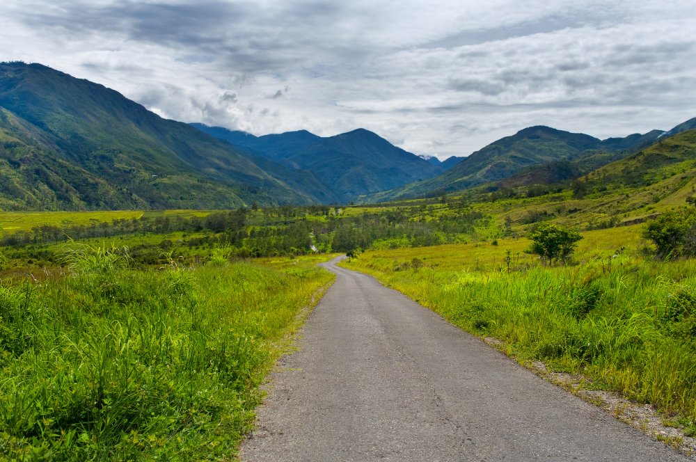 This image captures a serene valley landscape and Road in Papua New Guinea