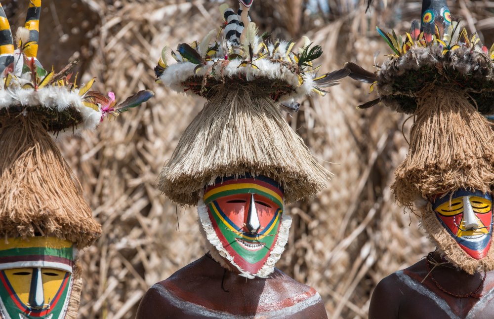 This image captures a persons from Melanesia wearing vibrant traditional face masks